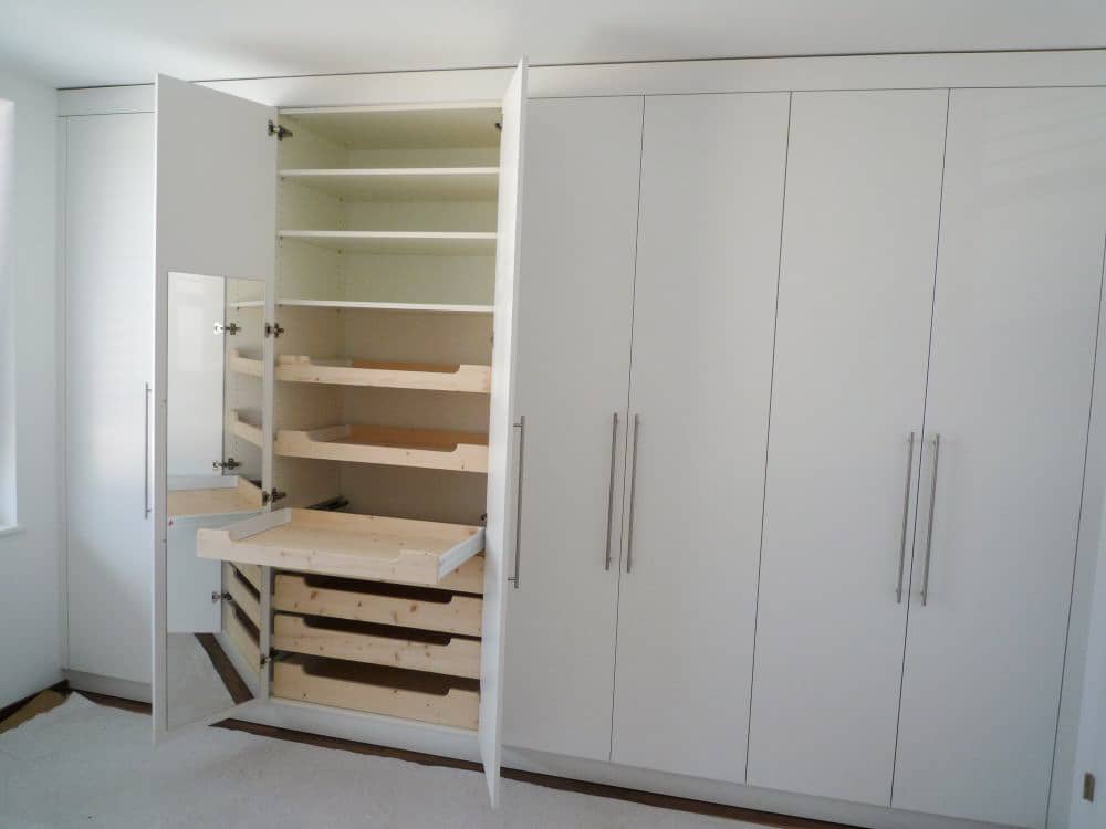 Ein Einbauwandschrank mit verschiedenen kleinen Schubladen drin. Alles ist aus Holz